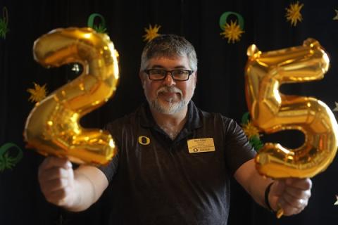 Employee holding balloons that make the number 25