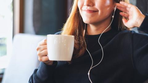 woman listening to music and drinking a warm beverage