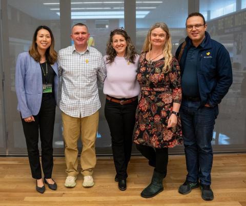 five people stand smiling in a row